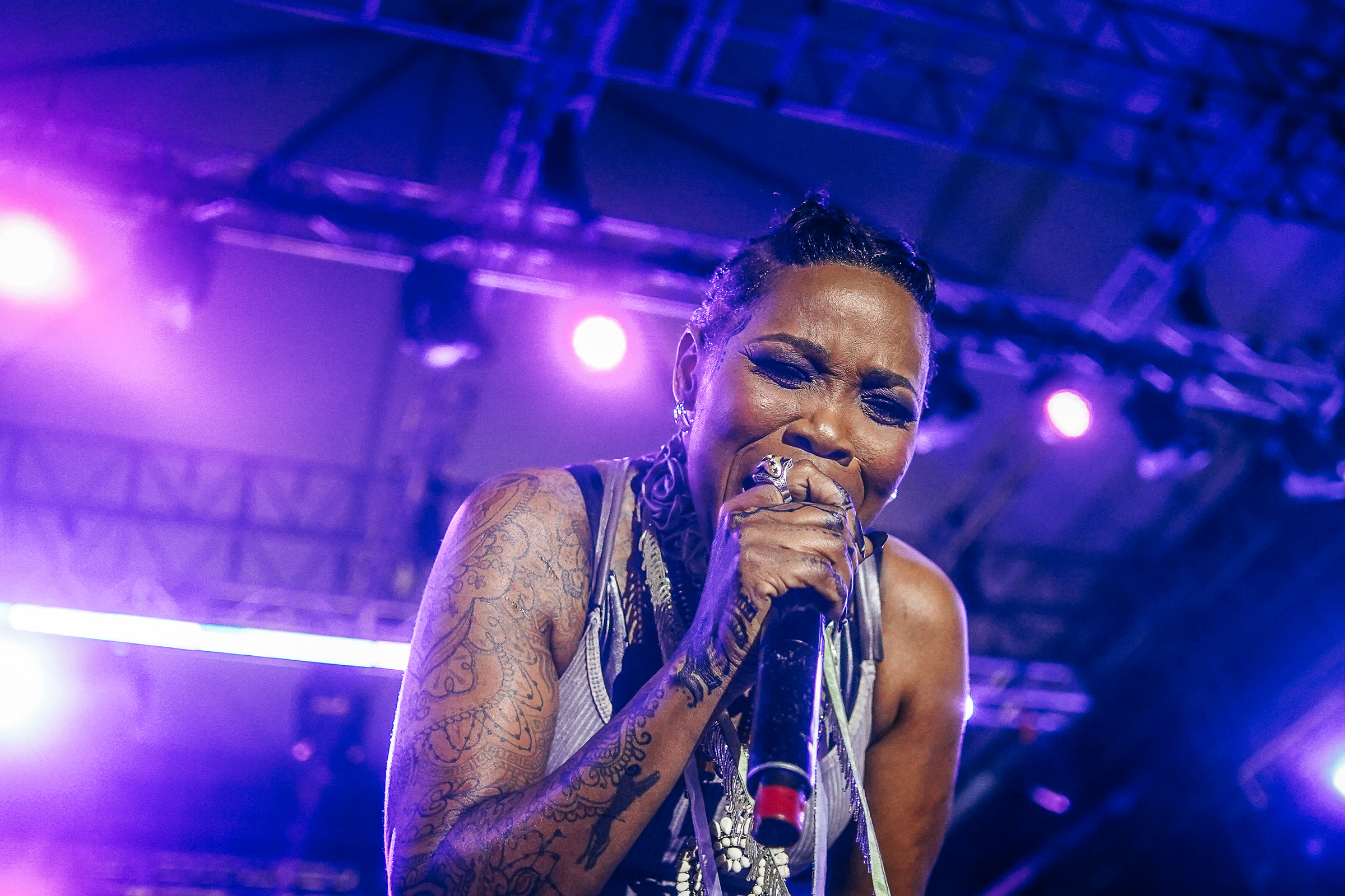 A singer performs with her eyes closed under purple stage light