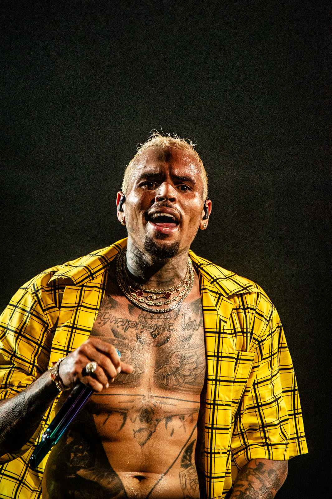 Breezy sings in an open yellow shirt