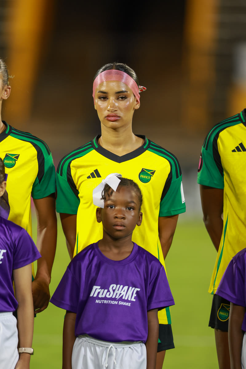 A Jamaica player stands with her young mascot for the line-up