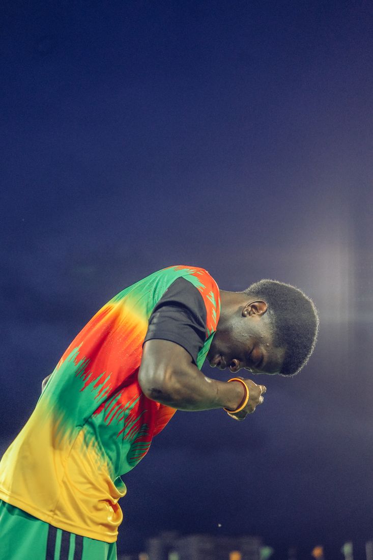 A player bows his head in the warm-up top against the evening sky