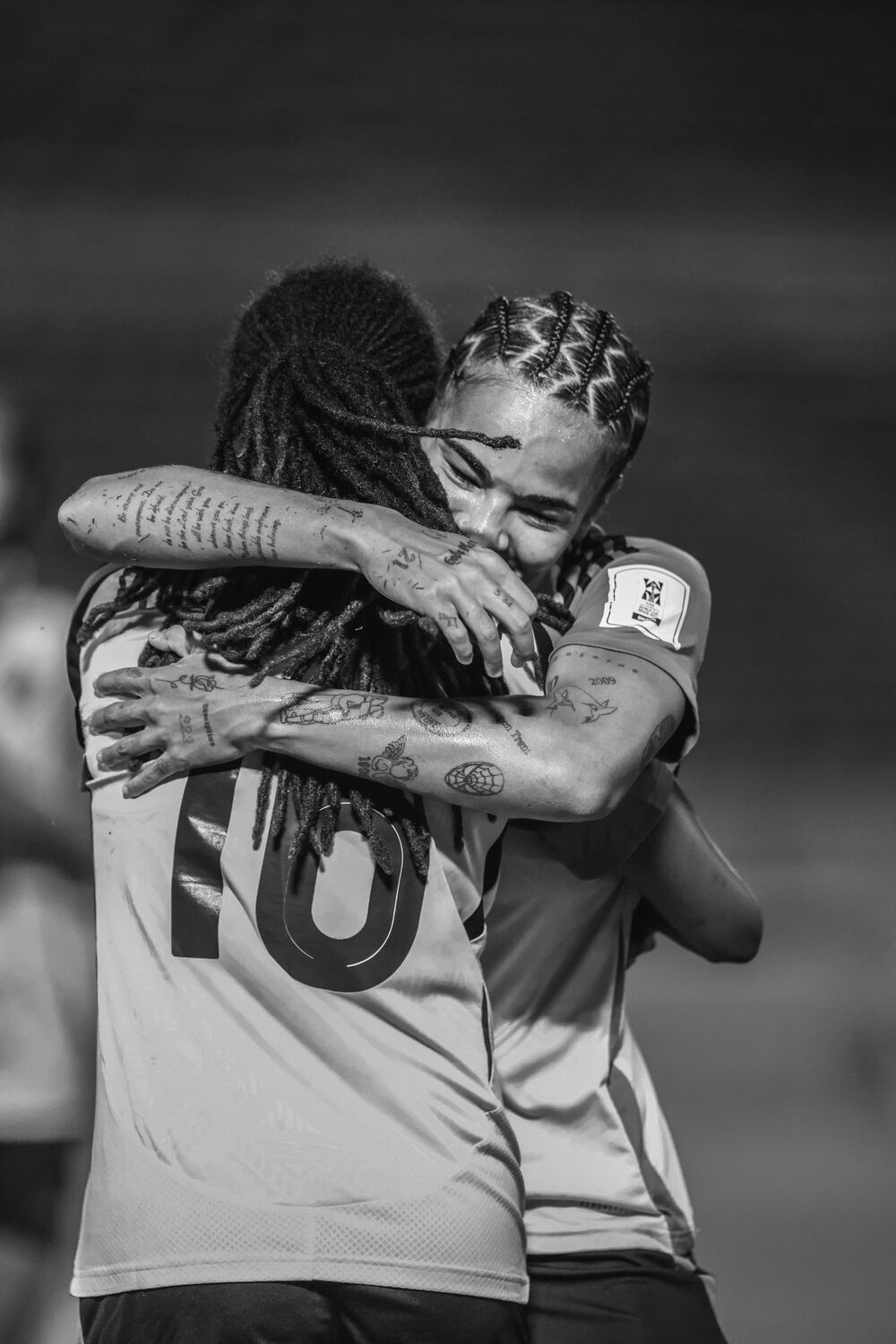 Two teammates embrace after the match, in black and white