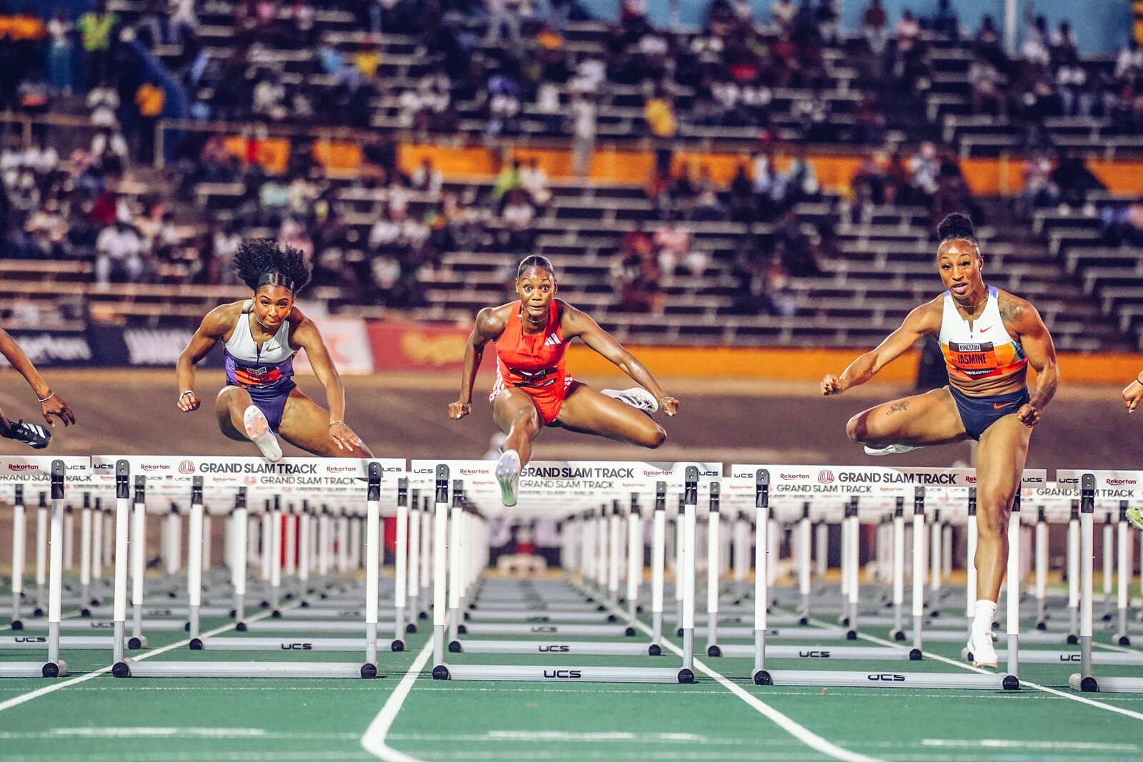 Three athletes clear the hurdles mid-flight at Grand Slam Track