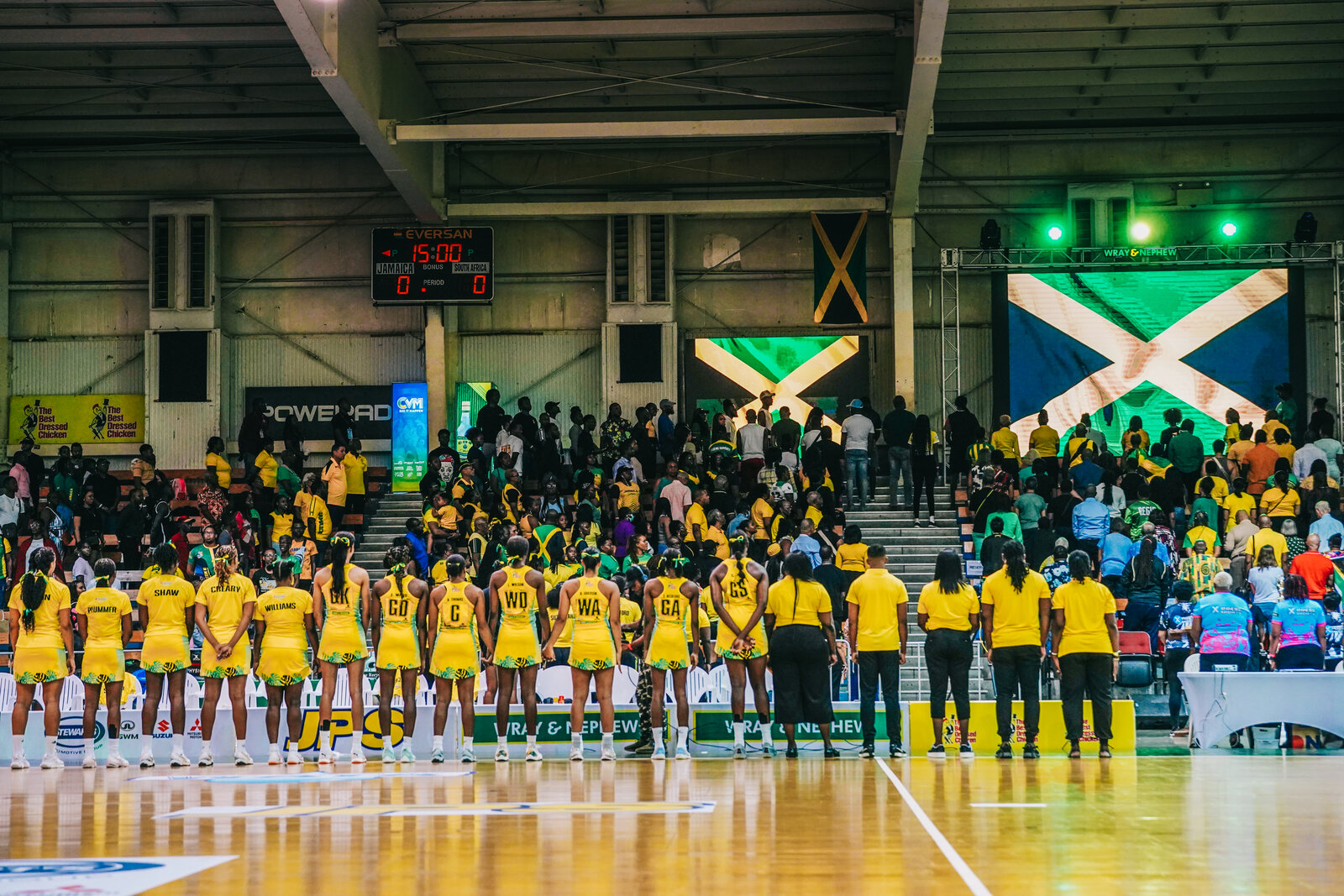 Jamaica netball teams line up for the anthem beneath a giant Jamaica flag