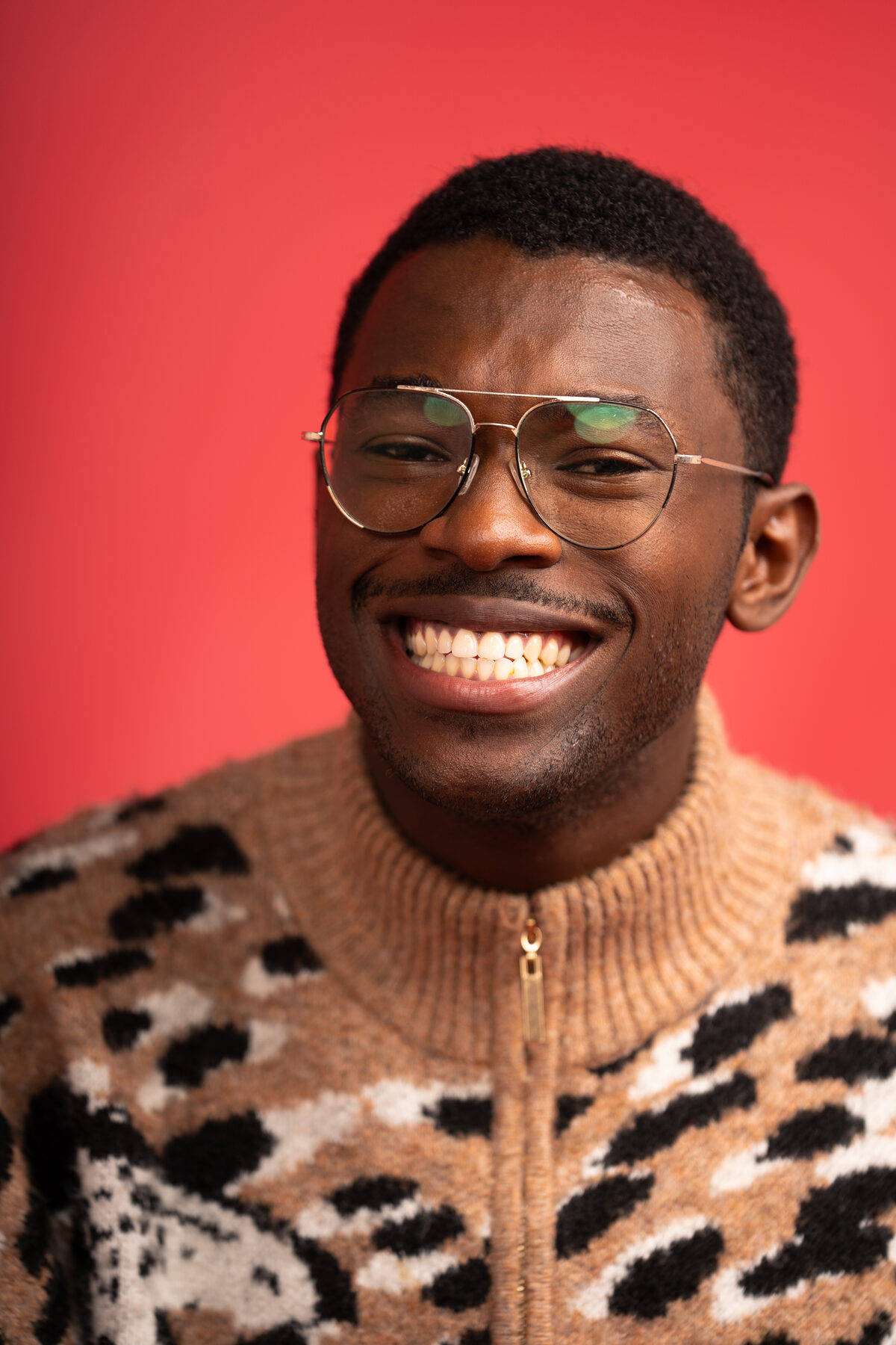 A man laughs broadly against a red backdrop
