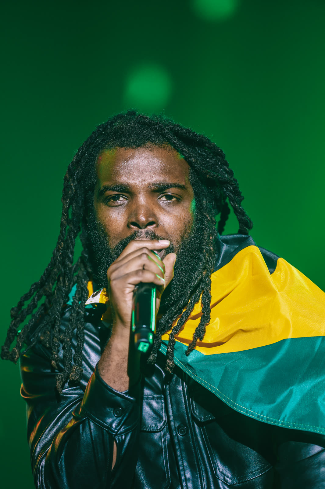 An artist sings with the Jamaica flag across his shoulder