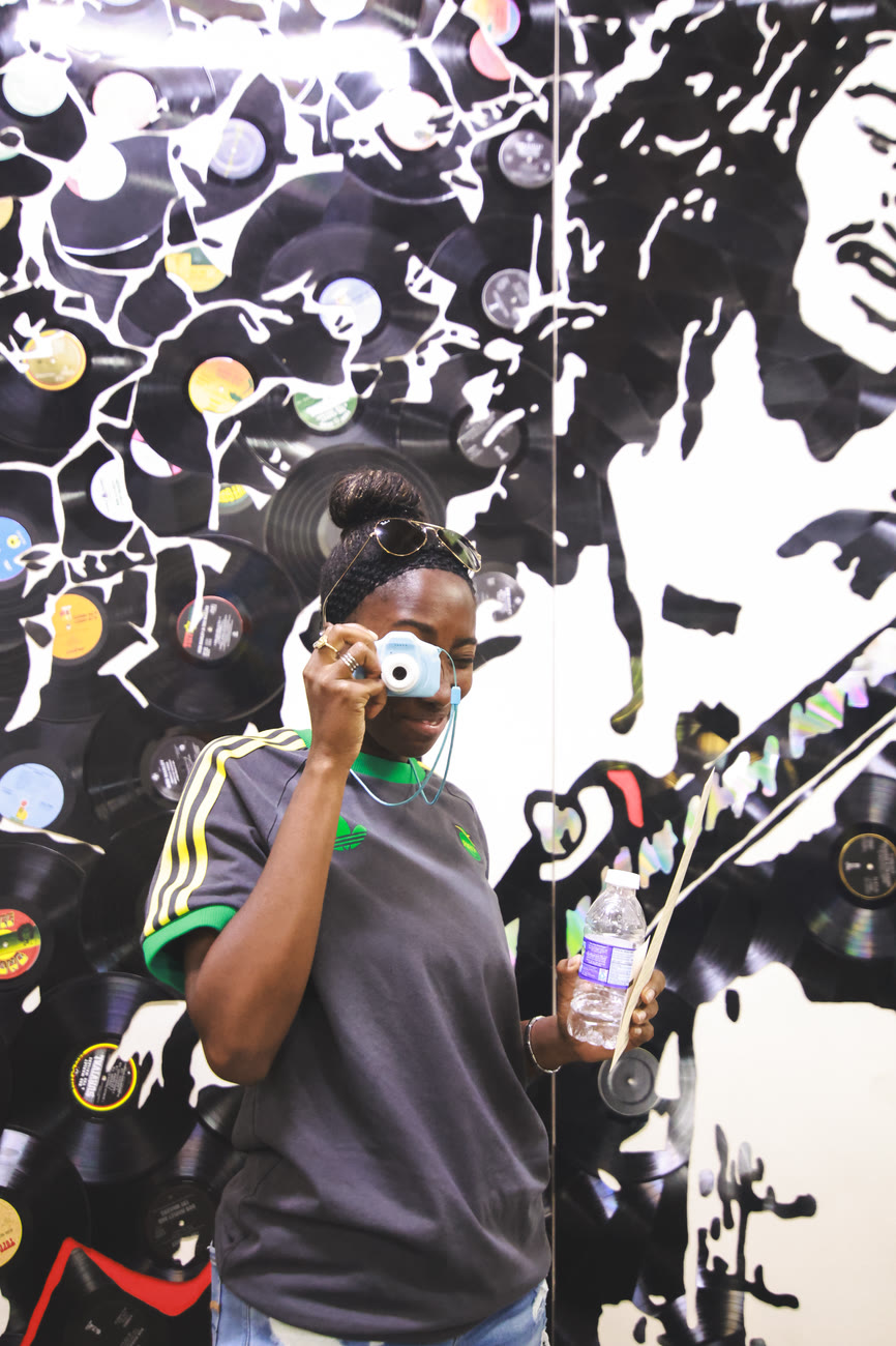 A player takes a photo in front of a Bob Marley mural
