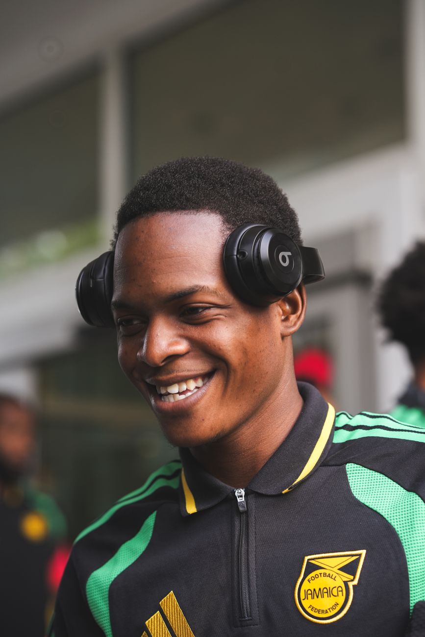 A smiling player in headphones as the squad leaves the team hotel