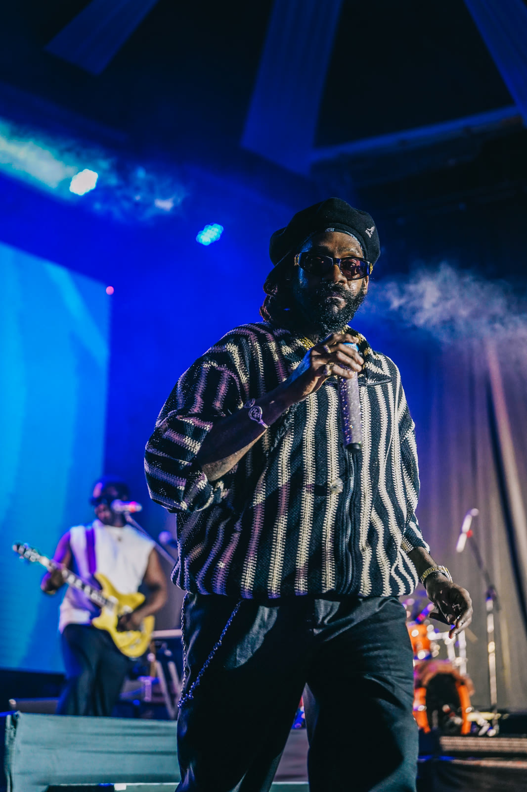 Tarrus Riley on stage under blue light with the band behind him