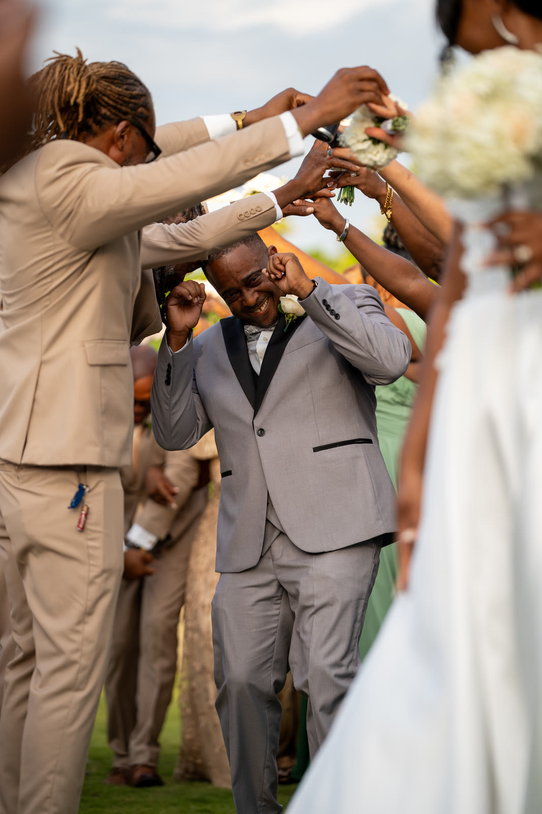 The groom ducks through an arch of raised hands