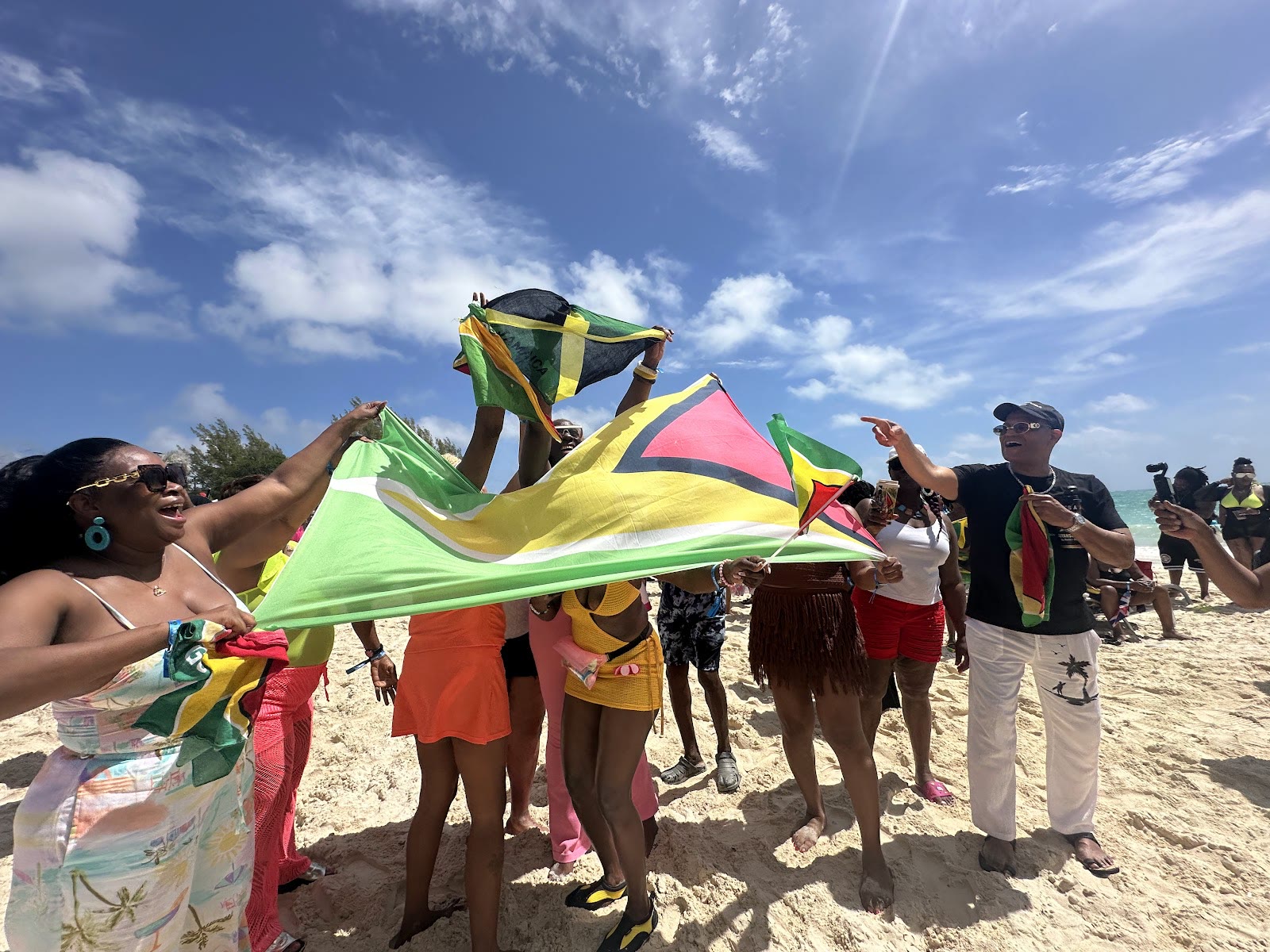 Guests wave Caribbean flags on the beach during a port day