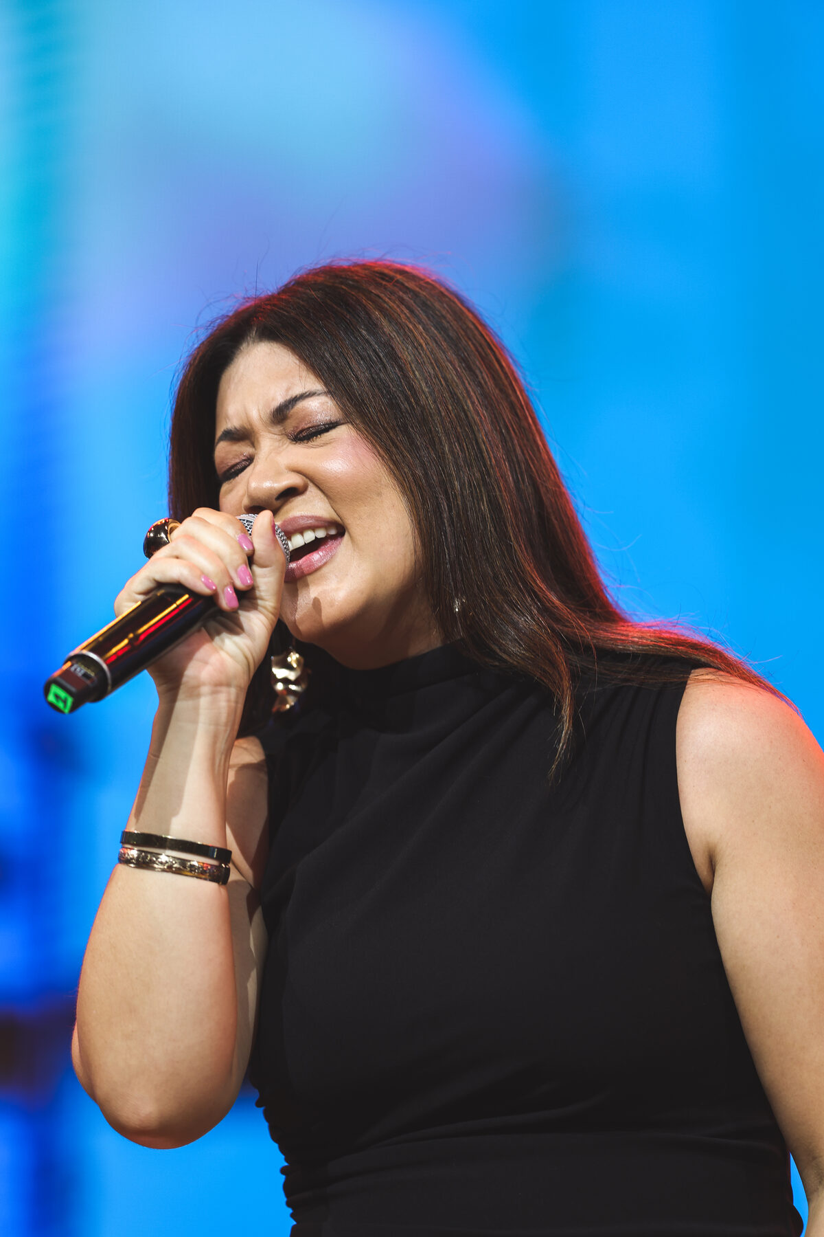 A vocalist sings under blue stage light