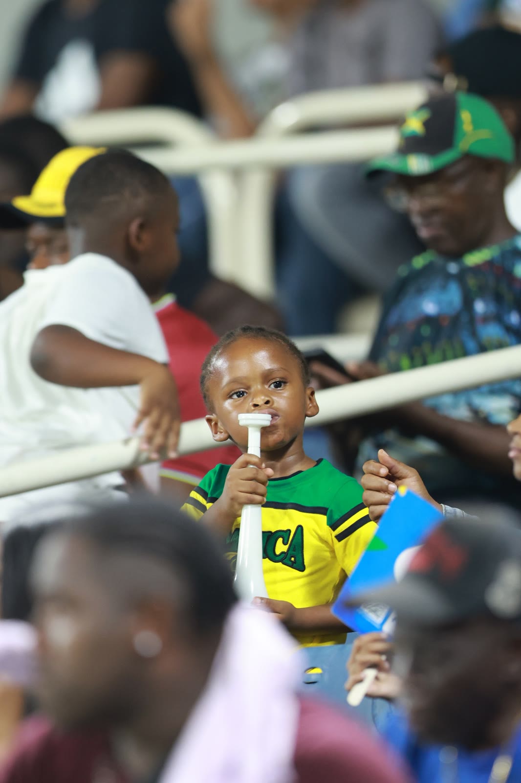 A young supporter blows a horn in a Jamaica shirt