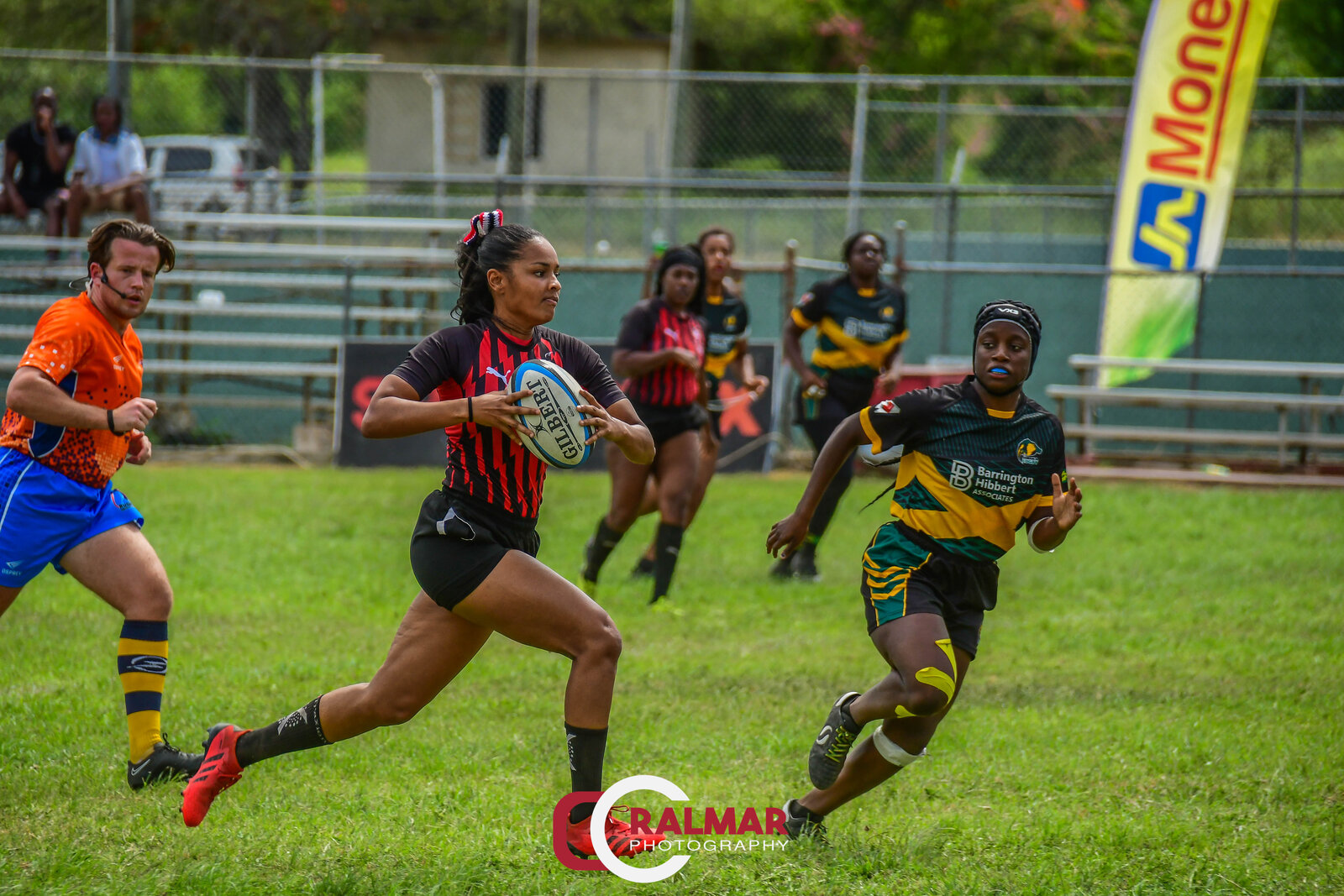 A women's rugby player drives forward with the ball