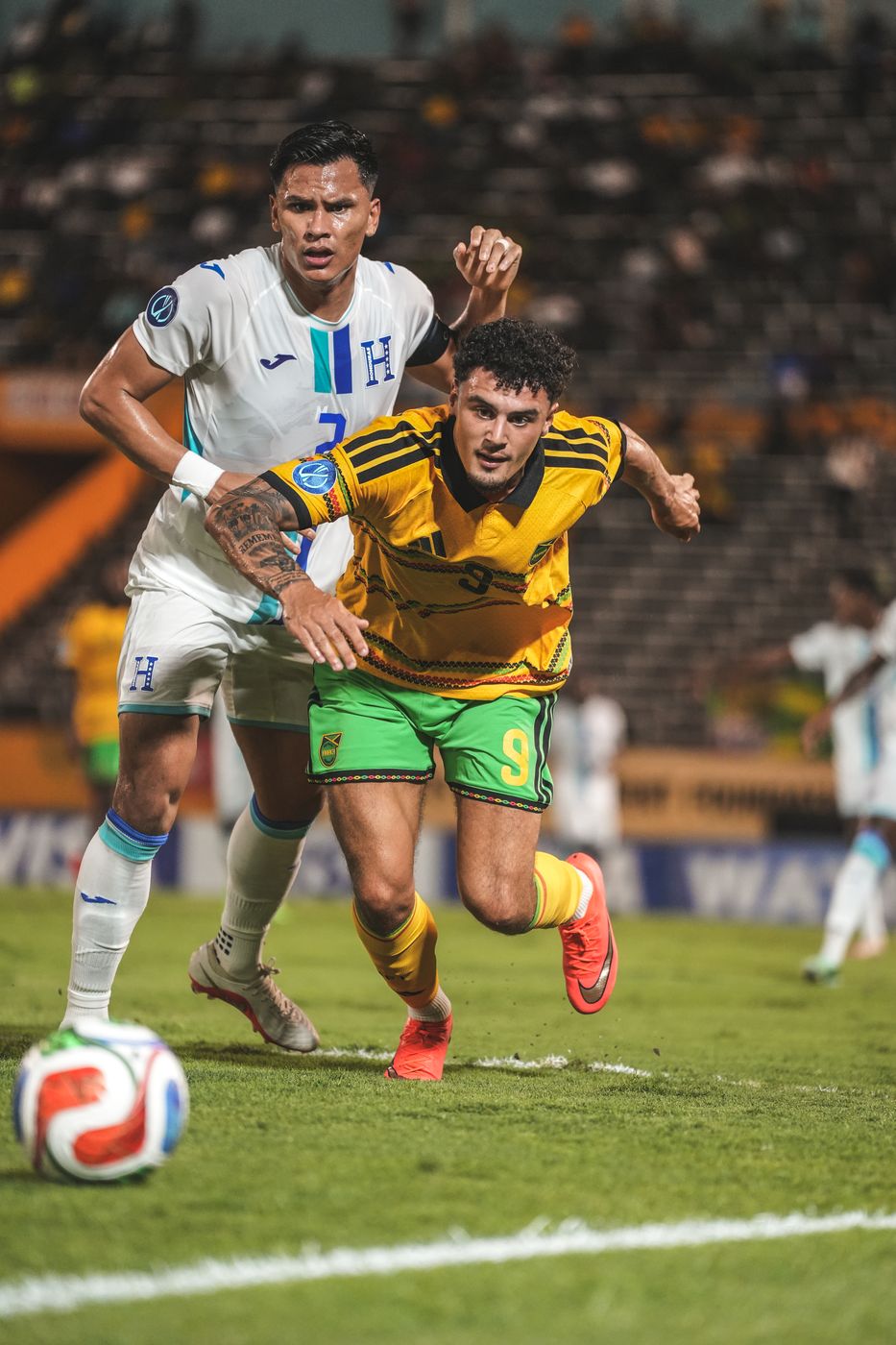A Jamaica attacker drives forward with a Honduras defender behind him