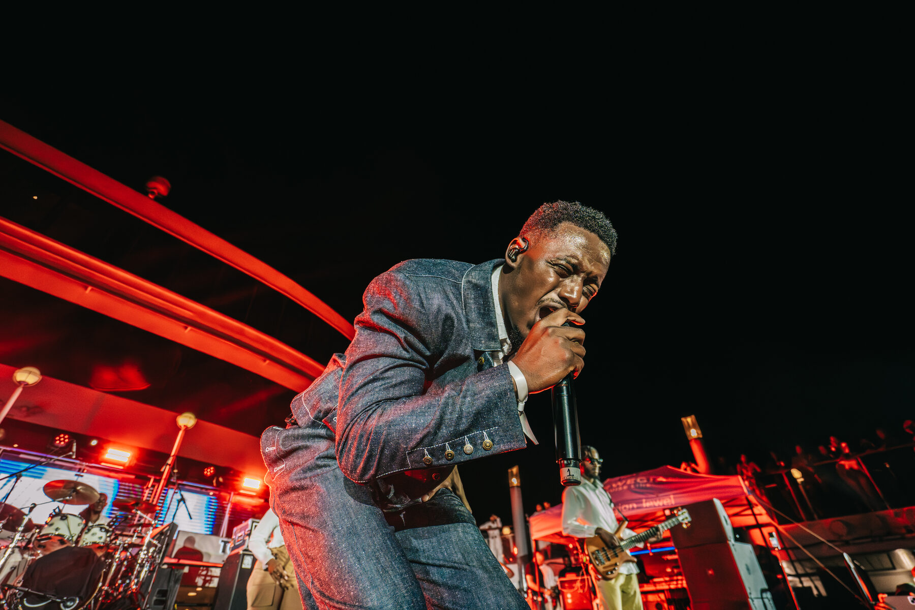 A performer crouches amid red laser light at a concert