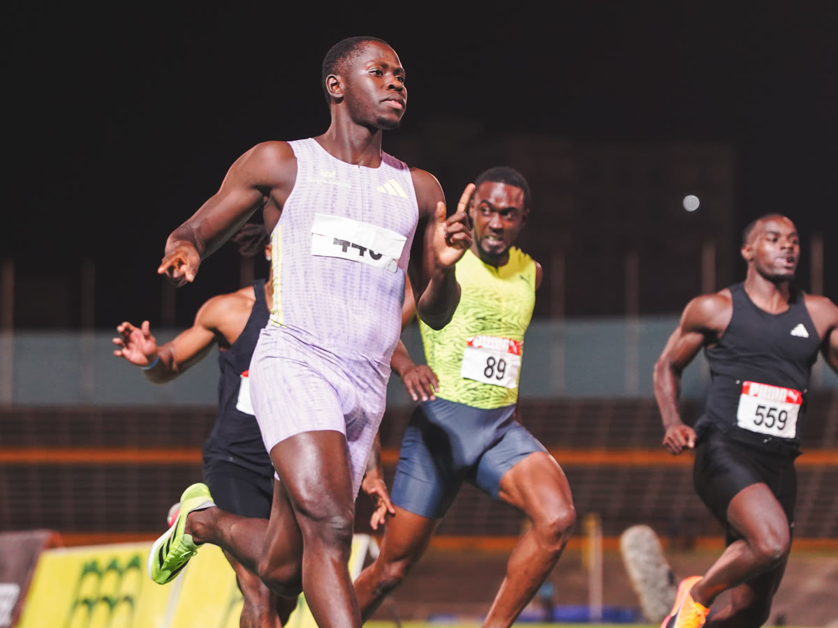 A sprinter drives through the finish under the lights at the JAAA National Trials