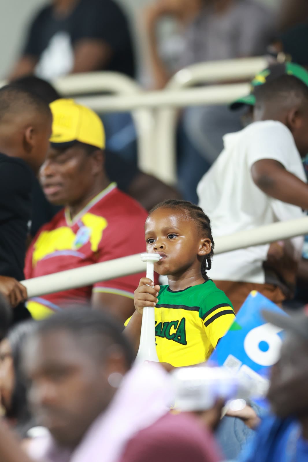 A young supporter in a Jamaica shirt blows a horn in the stands