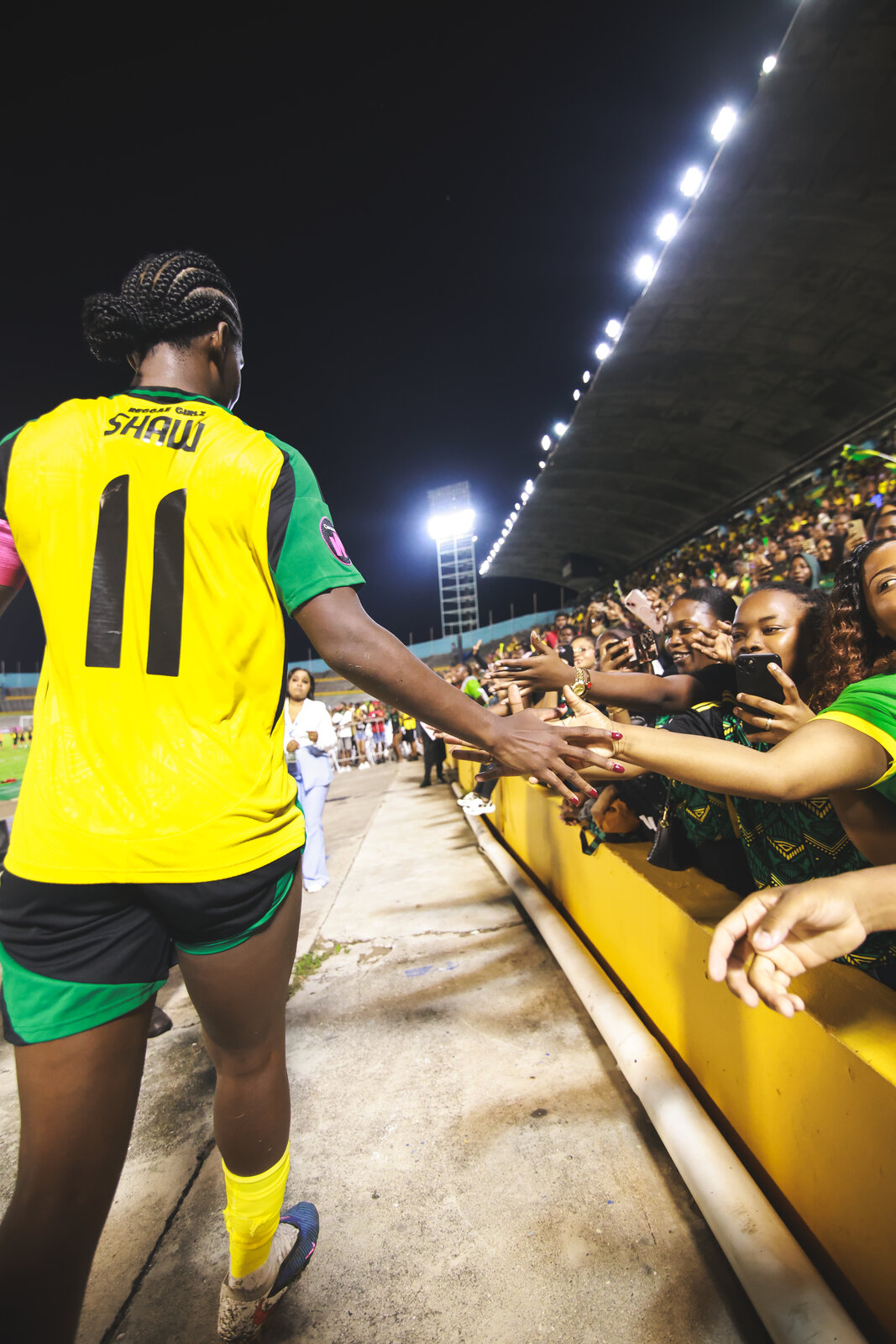 Khadija Bunny Shaw in the number eleven shirt high-fives fans at the stands