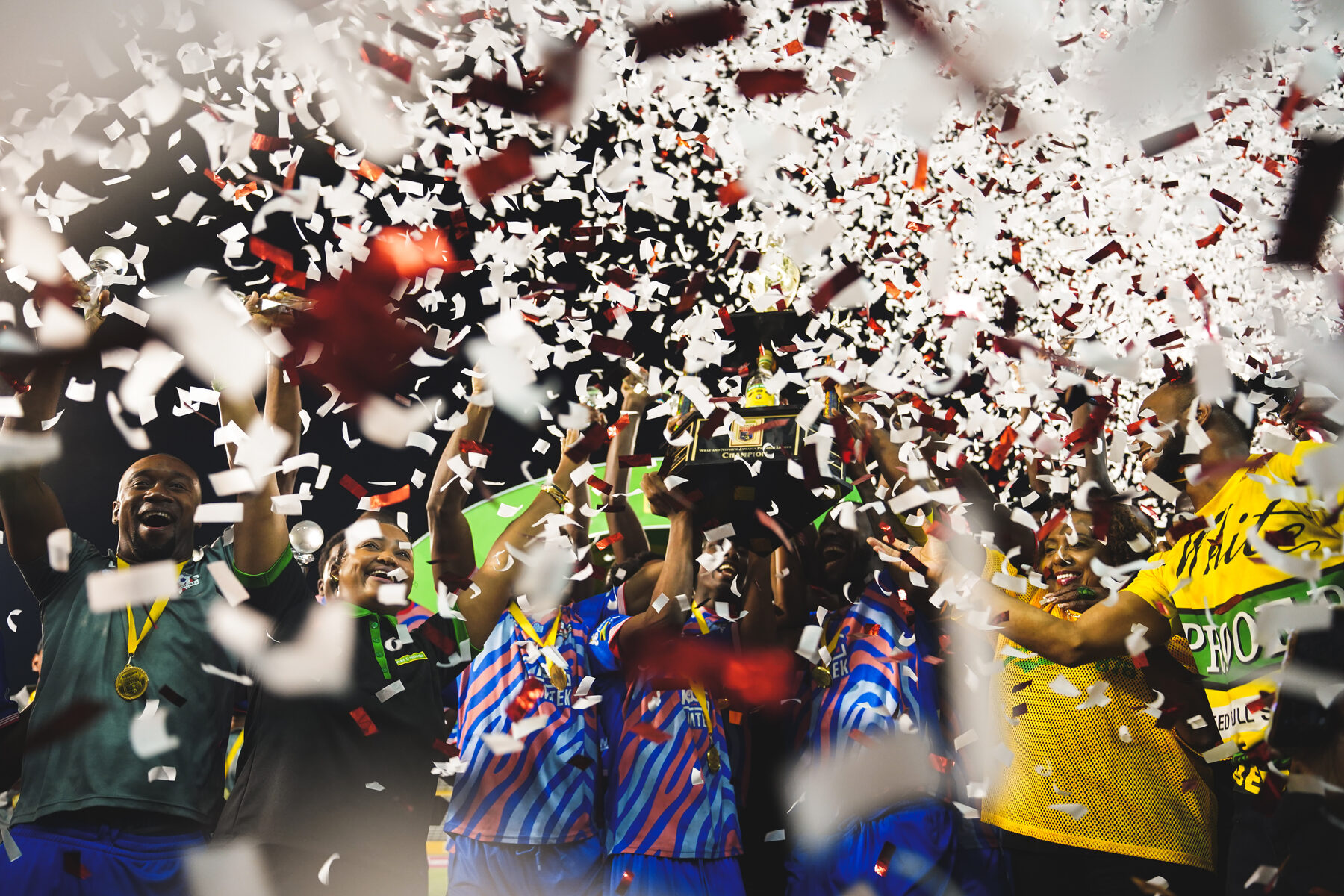 Players celebrate with a trophy under a storm of confetti