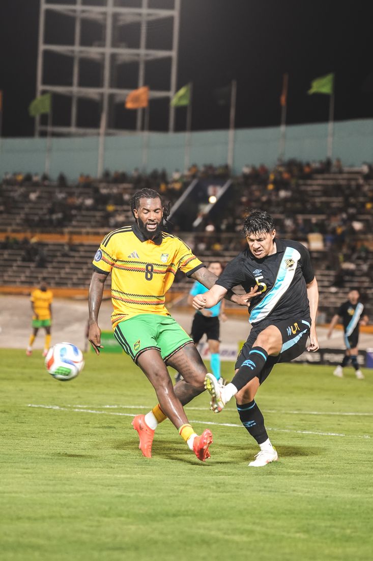 Number 8 shoots under pressure from a Guatemala defender