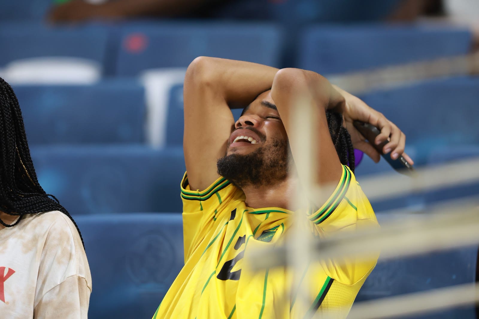 A supporter in a Jamaica shirt holds his head as the tension rises