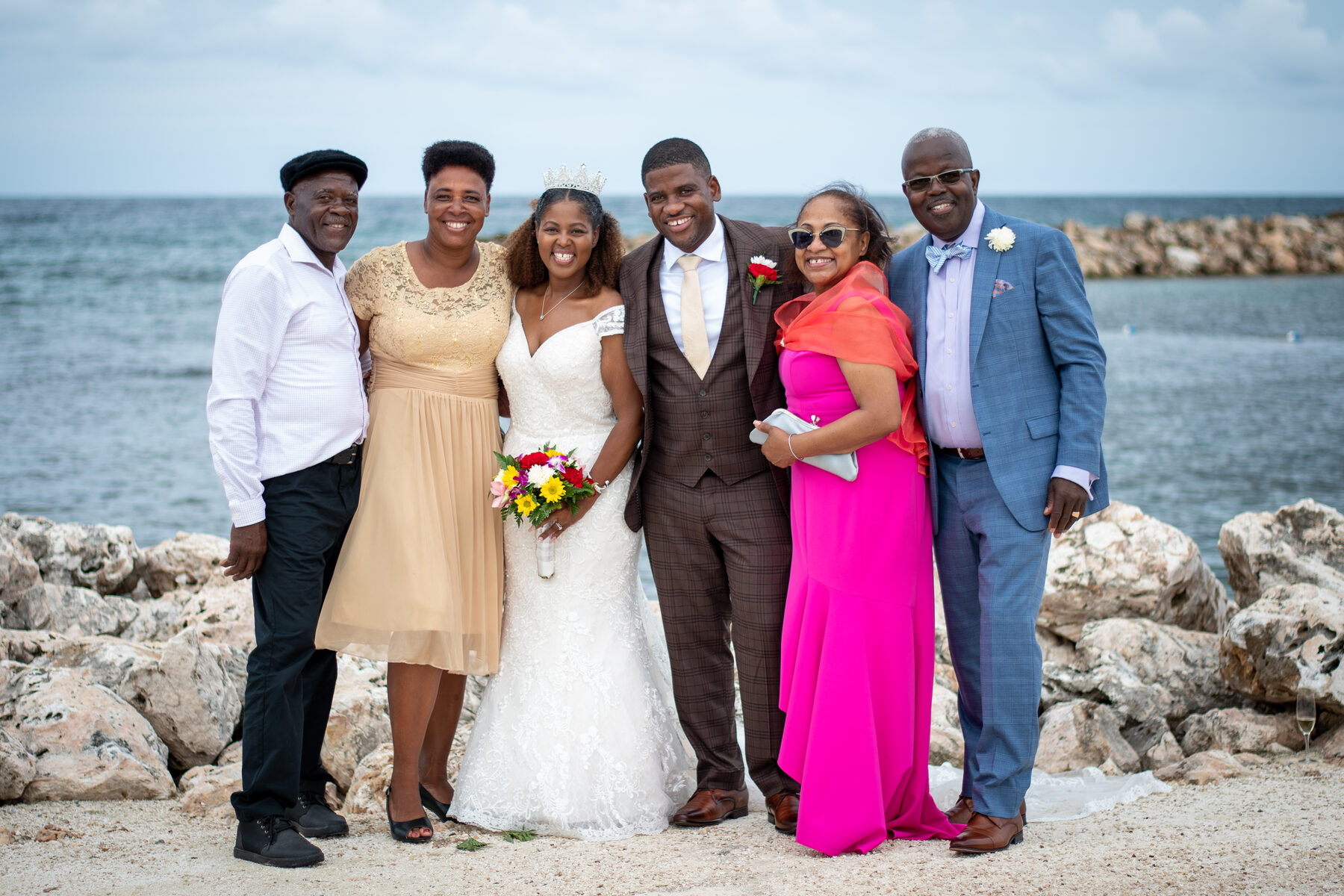 A seaside wedding group with a bride in a magenta gown
