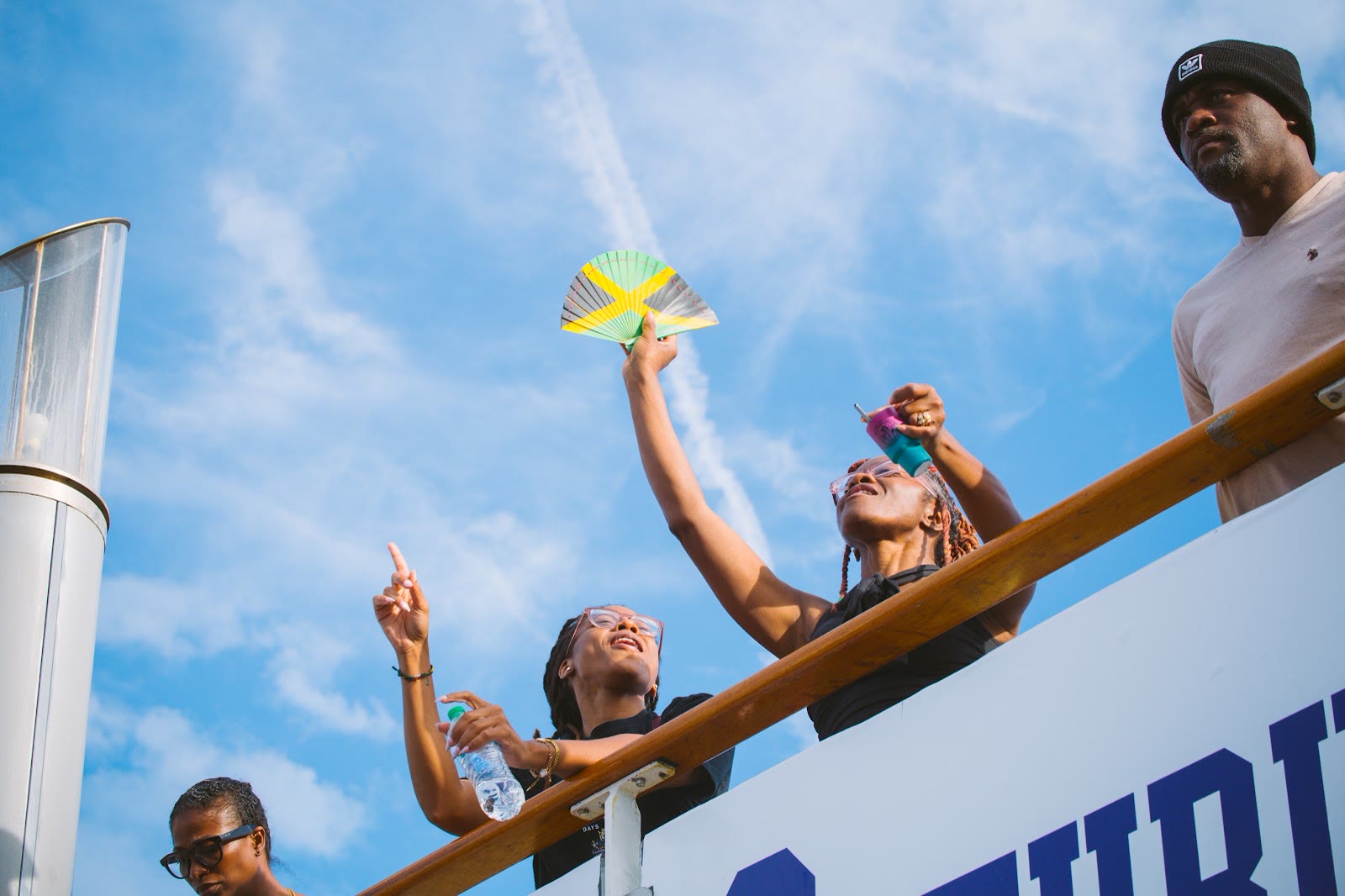 A guest celebrates at the ship's rail under a bright sky