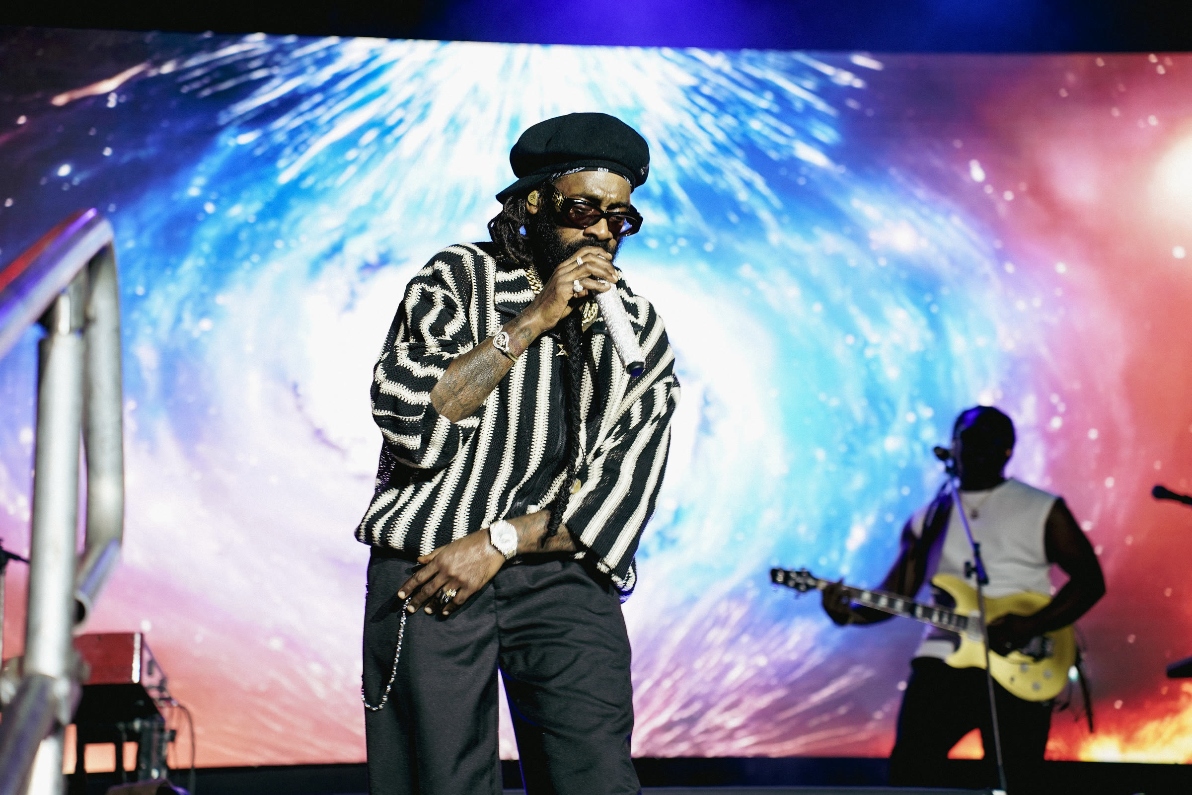 Tarrus Riley performs with the band in front of a bright screen