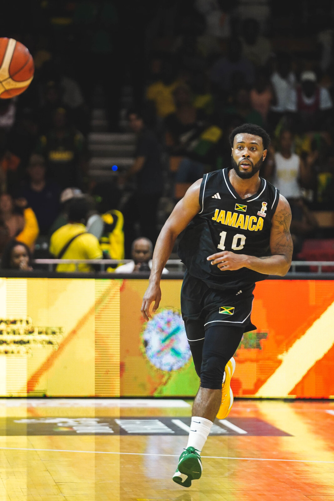 A Jamaica basketball player drives in the black and gold kit