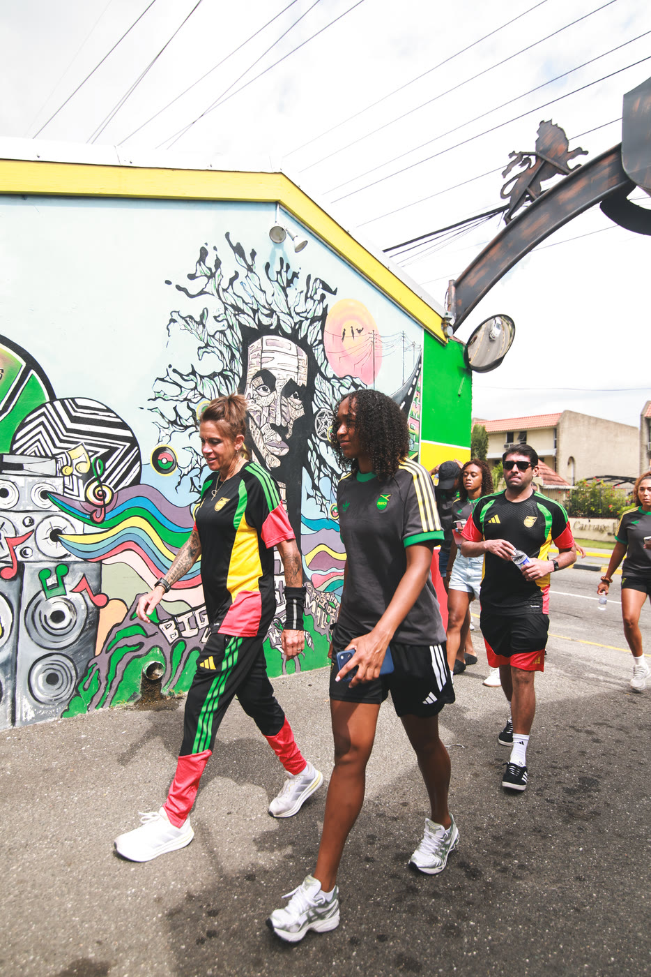 Reggae Girlz players walk past the Bob Marley mural at the museum entrance