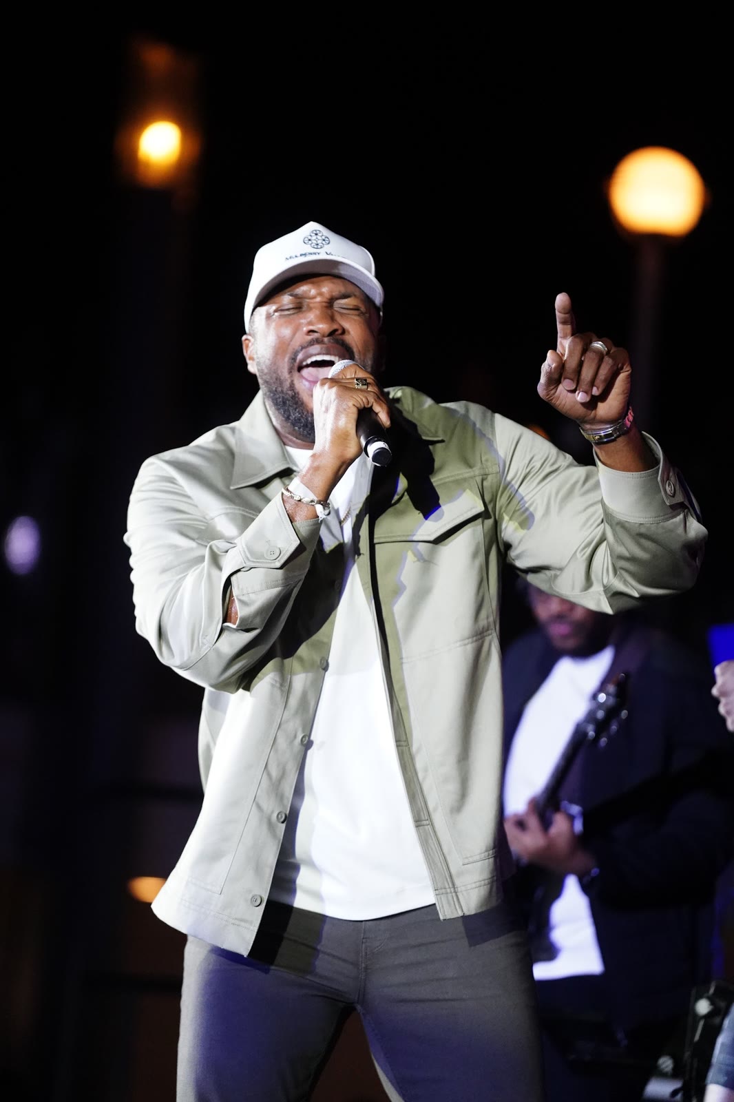 A headline artist in a white cap sings to the crowd on the night stage