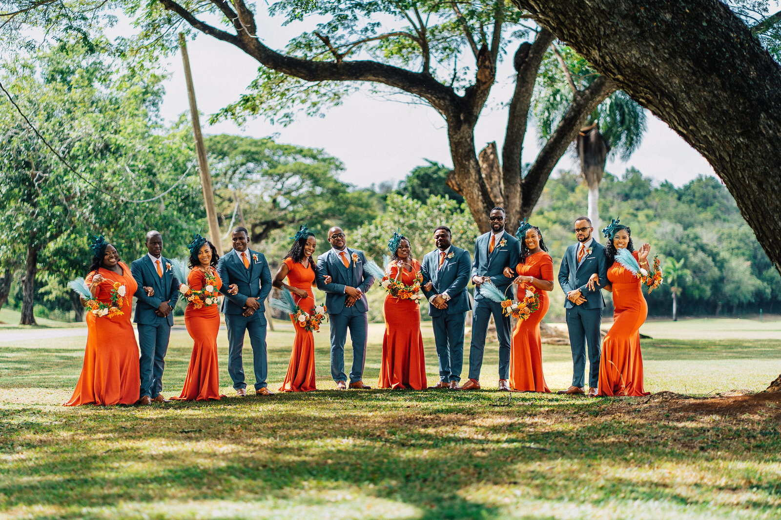 The full wedding party gathered beneath large trees