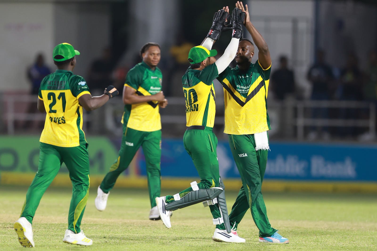 Kingsmen players jump and high-five to celebrate a wicket