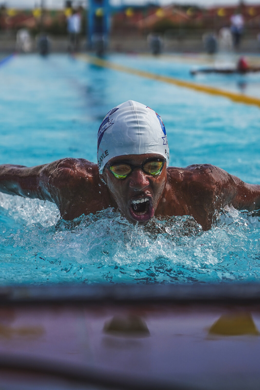 A swimmer in a white cap powers through the butterfly stroke