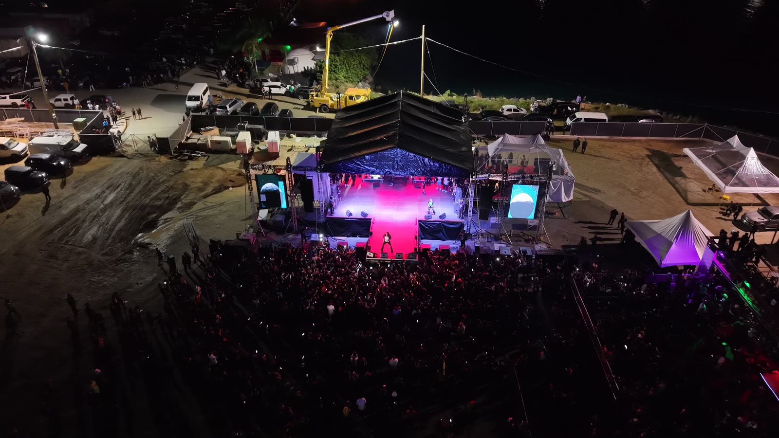 Aerial view at night of the Vybz Kartel and Friends stage in Tortola, lit pink and blue above the crowd
