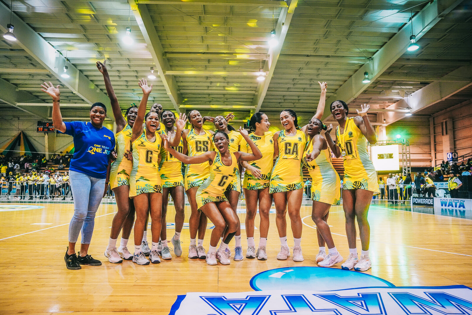 The Jamaica netball squad celebrates in a line on court