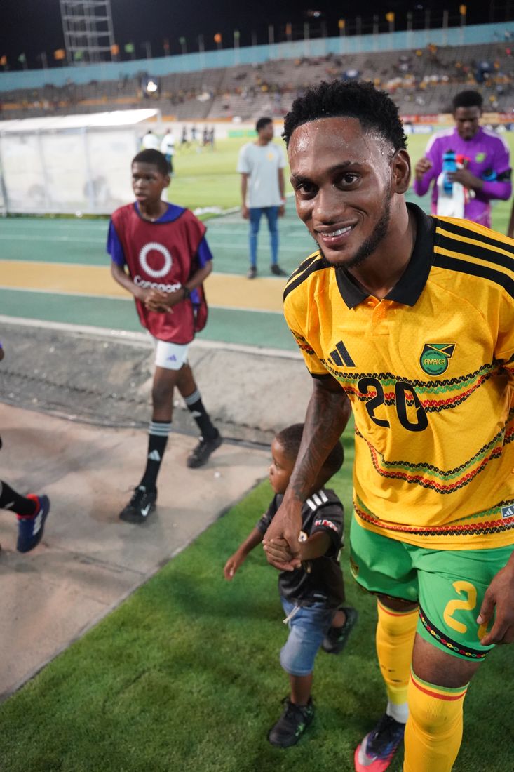 Number 20 smiles on the touchline beside a ball kid